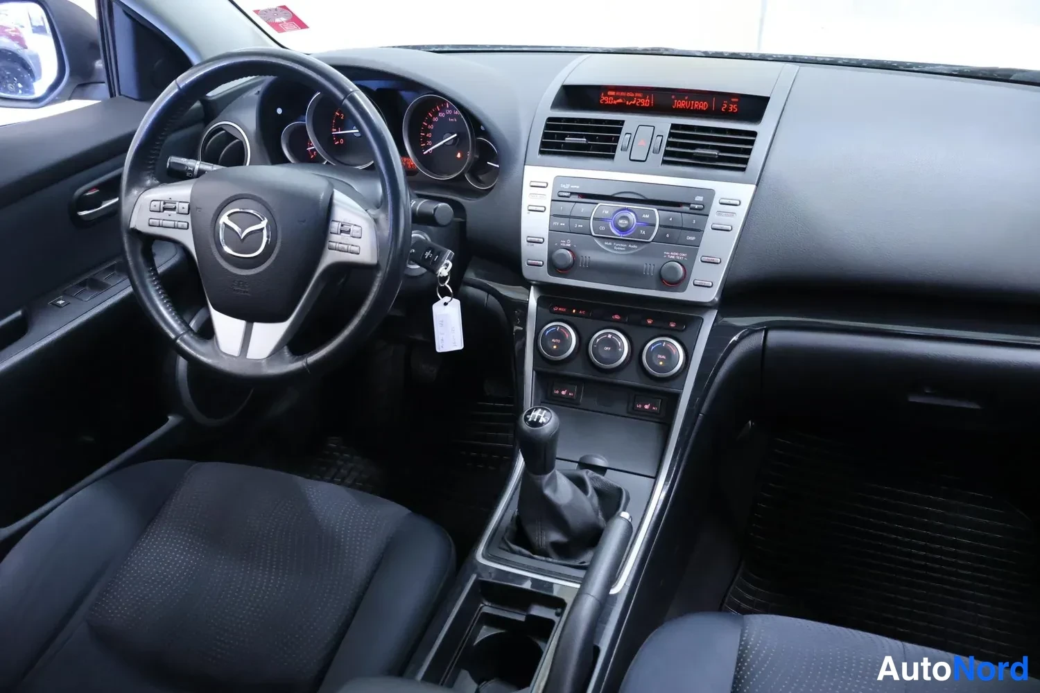 Muu: Mazdan ohjaamo: Mazda-ohjauspyörä, analogiset mittarit, keskikonsolissa radio ja manuaalivaihteisto.