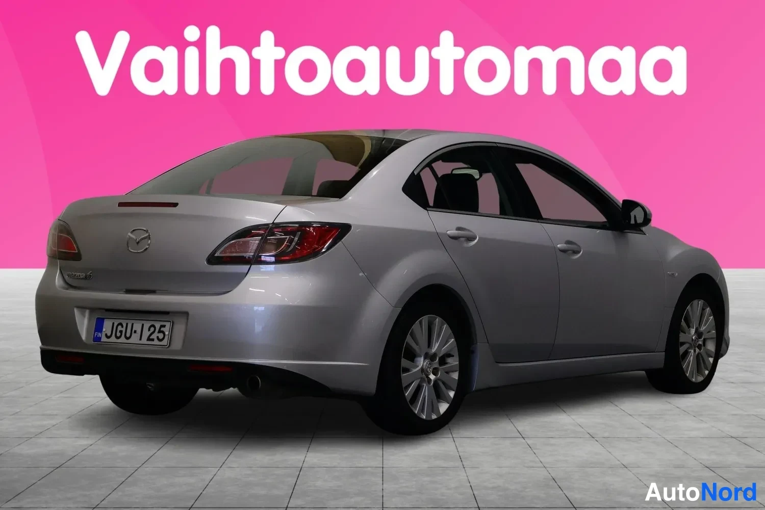 Takaviisto: Hopeanharmaa Mazda 6 -sedan takaa oikealta kuvattuna, rekisterikilpi.