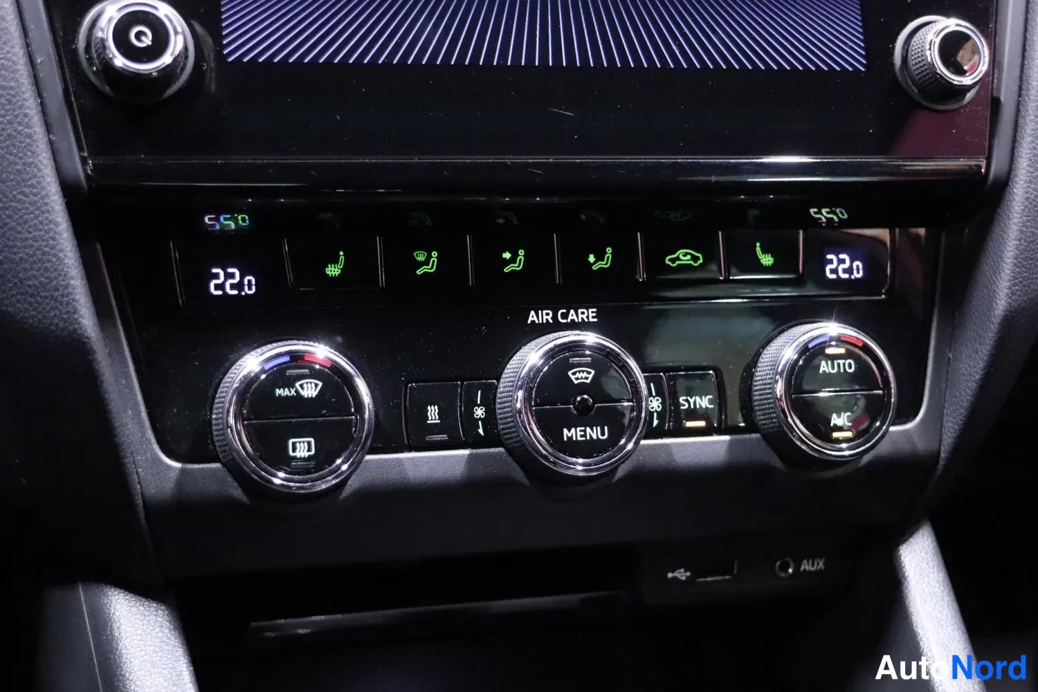 Muu: Auton ilmastointipaneeli kahdella säätörullalla, lämpötila 22,0, merkeissä AUTO, A/C, SYNC ja AIR CARE sekä USB- ja AUX-liittimet.