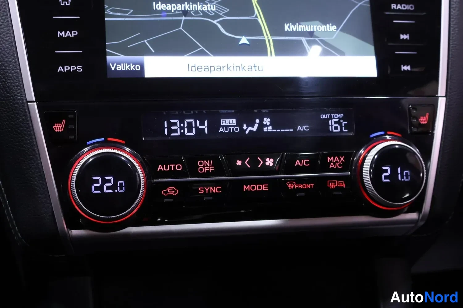 Muu: Kaksoisilmastointipaneeli näytöillä 22.0 ja 21.0, A/C, AUTO, SYNC, MODE ja MAX A/C -painikkeet; ulkolämpötila 16°C ja kello 13:04.