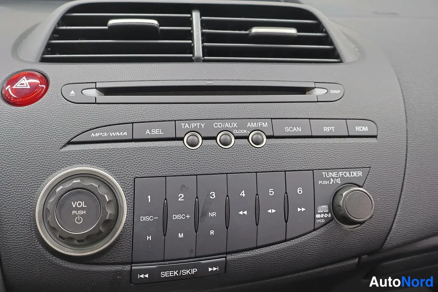 Yksityiskohta: Honda Civicin kojelaudan radiopaneeli, jossa MP3/WMA-merkinnät, CD/AUX-toiminto, esiasetusnumerot 1–6 ja VOL-PUSH-säädin.