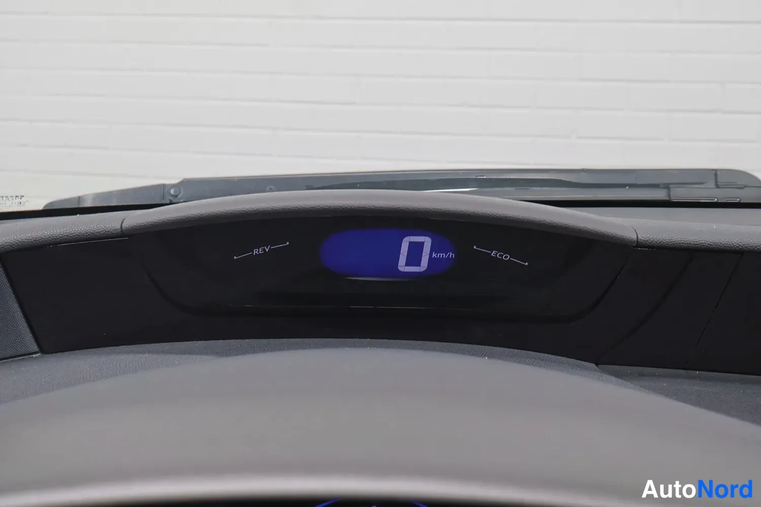 Yksityiskohta: Auton yläkojelaudan digitaalinäyttö näyttää nopeutta 0 km/h, kanssa REV- ja ECO-merkinnät.