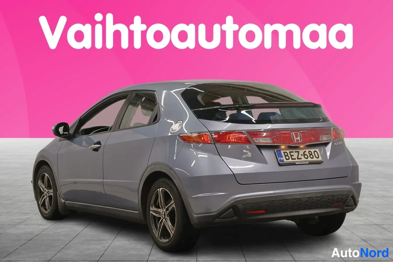 Takaviisto: Harmaansininen viisiovinen hatchback takaviistosta kuvattuna, takavalojen ja rekisterikilven näkyessä.