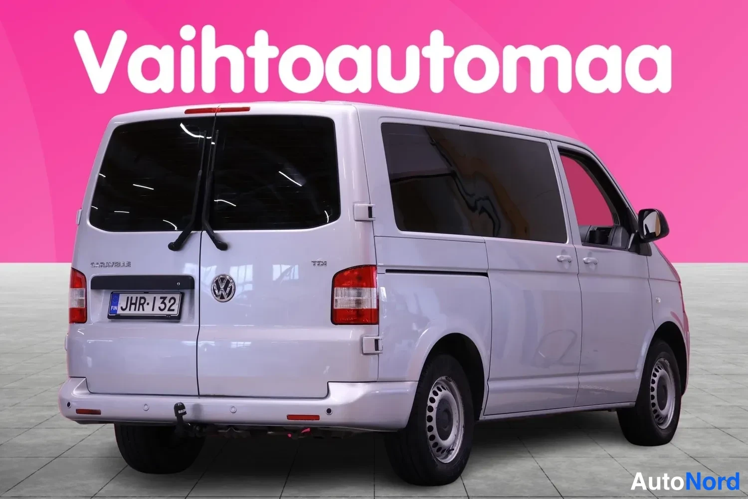 Takaviisto: Valkoinen Volkswagen pakettiauto takaa vasemmalta, takavirtaoven ikkunoissa heijastuksia, rekisteri