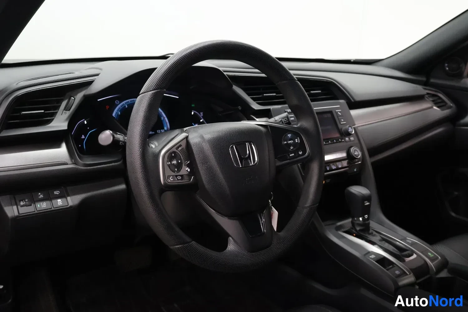 Muu: Auton ohjaamo: Honda-merkillinen ohjauspyörä, mittaristo ja keskikonsoli automaattivaihteistolla.