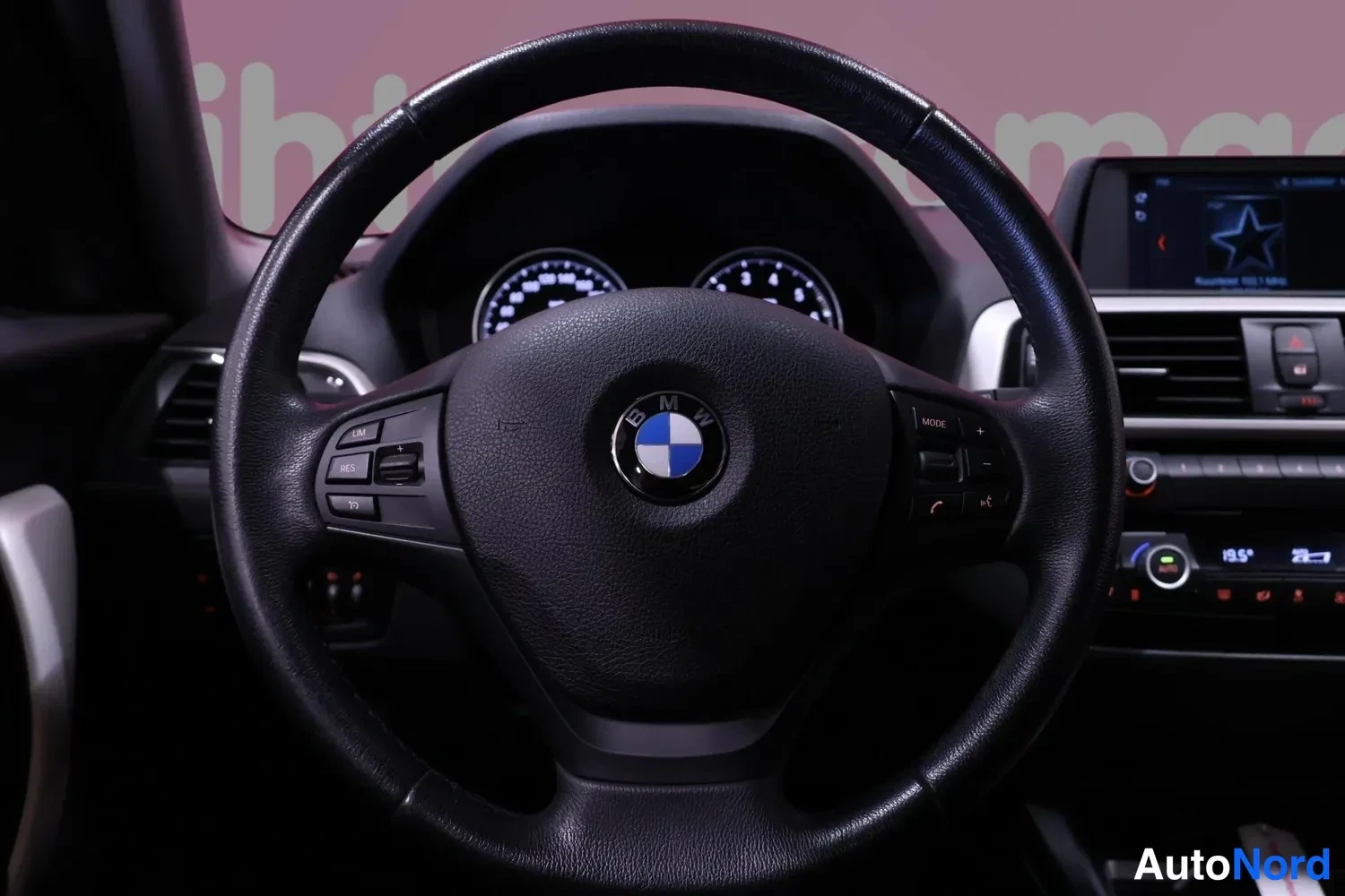 Etuviisto, nokka oikealle: Tarkennettu kuva BMW-ohjauspyörästä ja mittaristosta, kojelaudan näyttö oikealla.