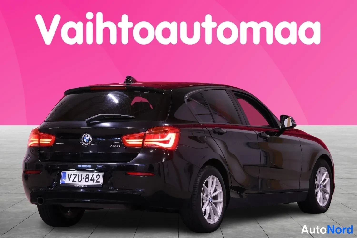 Takaviisto: Musta BMW 1-sarjan viistoperäinen auto kuvattuna takaviistolta; takavalot, tavaratilan kannen 118i-merkki ja rekisterikilpi näkyvät.