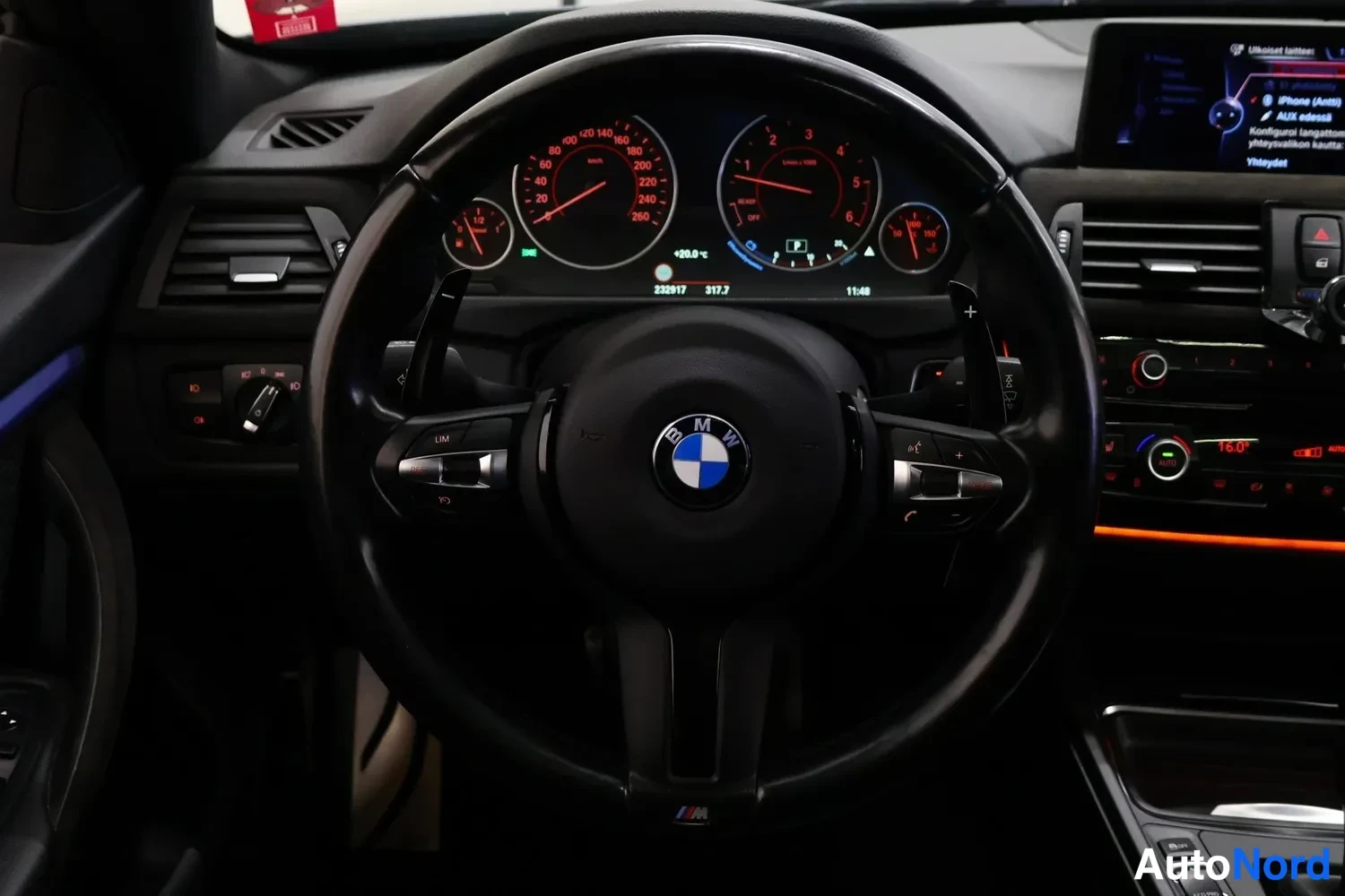 Muu: Ohjauspyörä ja mittaristo BMW:n sisätilassa, keskinäyttö näkyvillä oikealla.