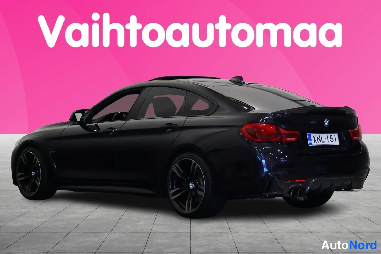 Takaviisto: Tummansininen BMW-neliovi takaosa ja vasen kylki vinossa kulmassa, takavalot ja rekisterikilpi näkyvät.