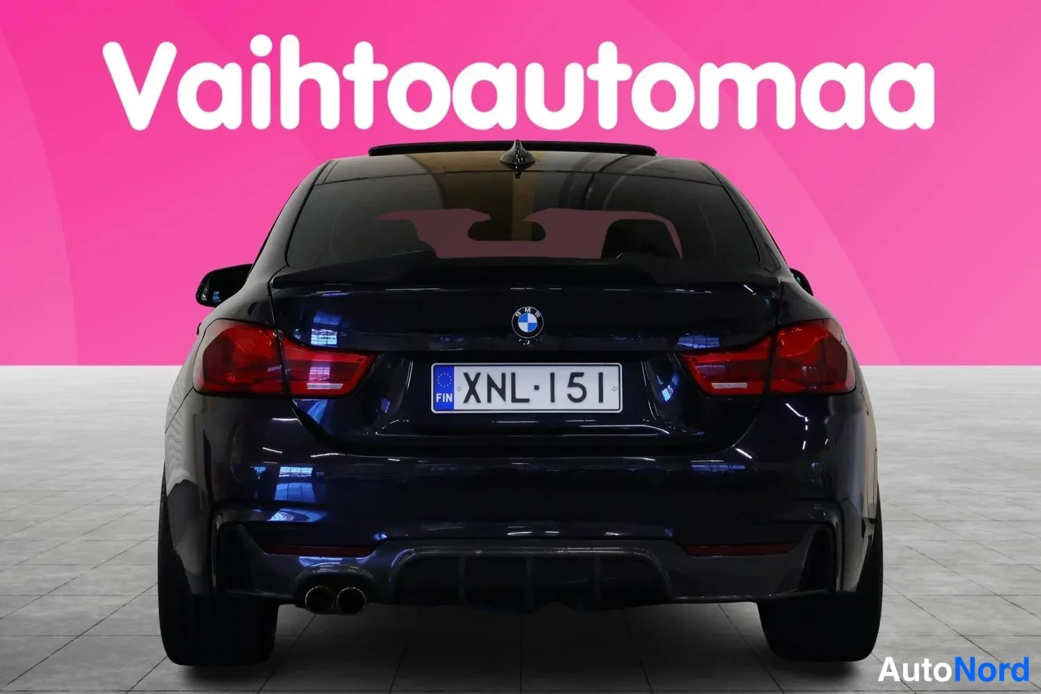 Takaa: Tummansininen BMW:n perä suoraan takaa, takavalot, takapuskuri, pakoputket ja rekisterikilpi näkyvät.
