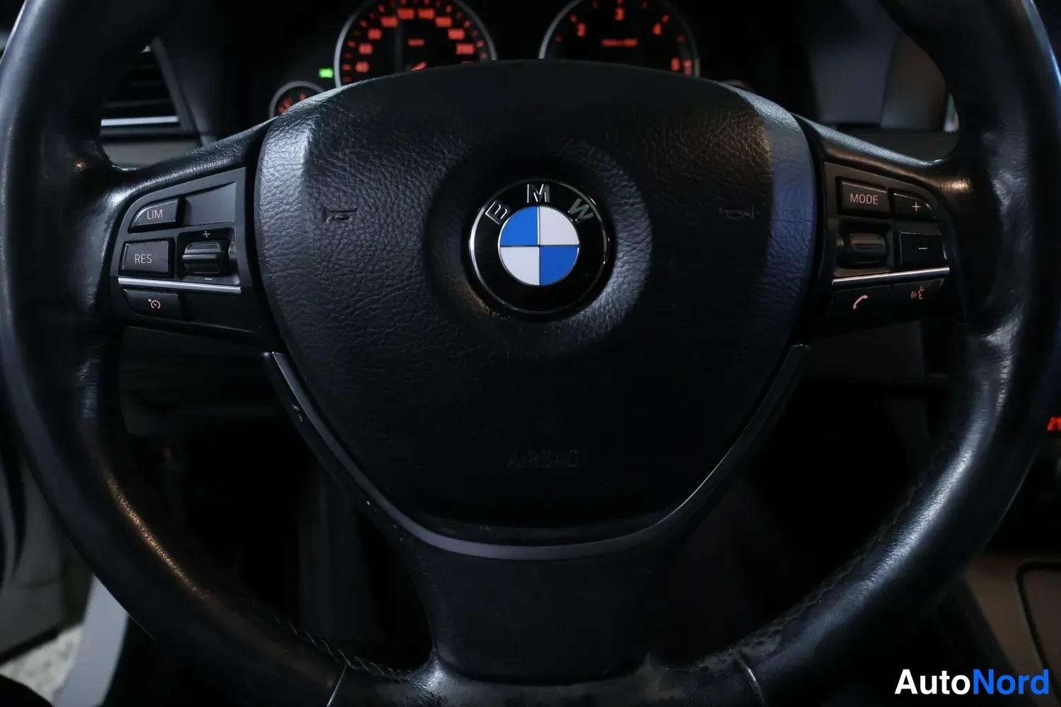 Muu: Ohjauspyörän lähikuva, keskellä BMW:n logo, ohjainpainikkeet vasemmalla ja oikealla.
