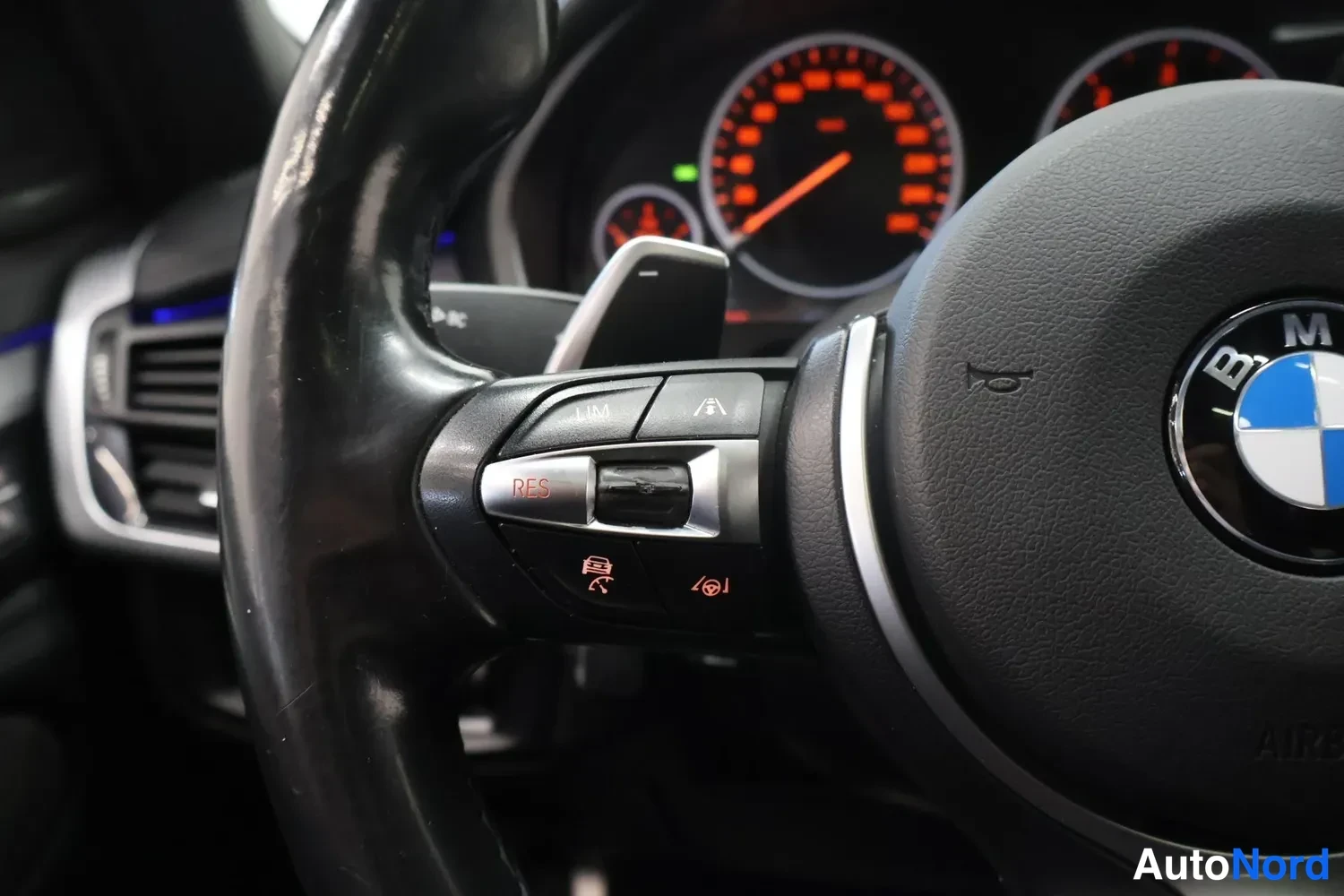 Muu: Rattirakko BMW-merkillä ja M-rattivaihto; rattleista taakse pikkuna näkyy punainen nopeusmittari.