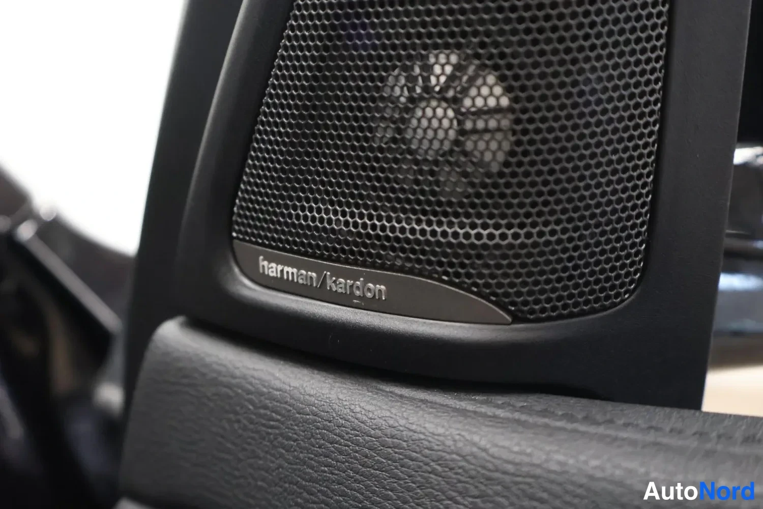 Muu: Harman/kardon-merkittyä korikekaiutinta mustaa kalvoa vasten lähikuvasta.