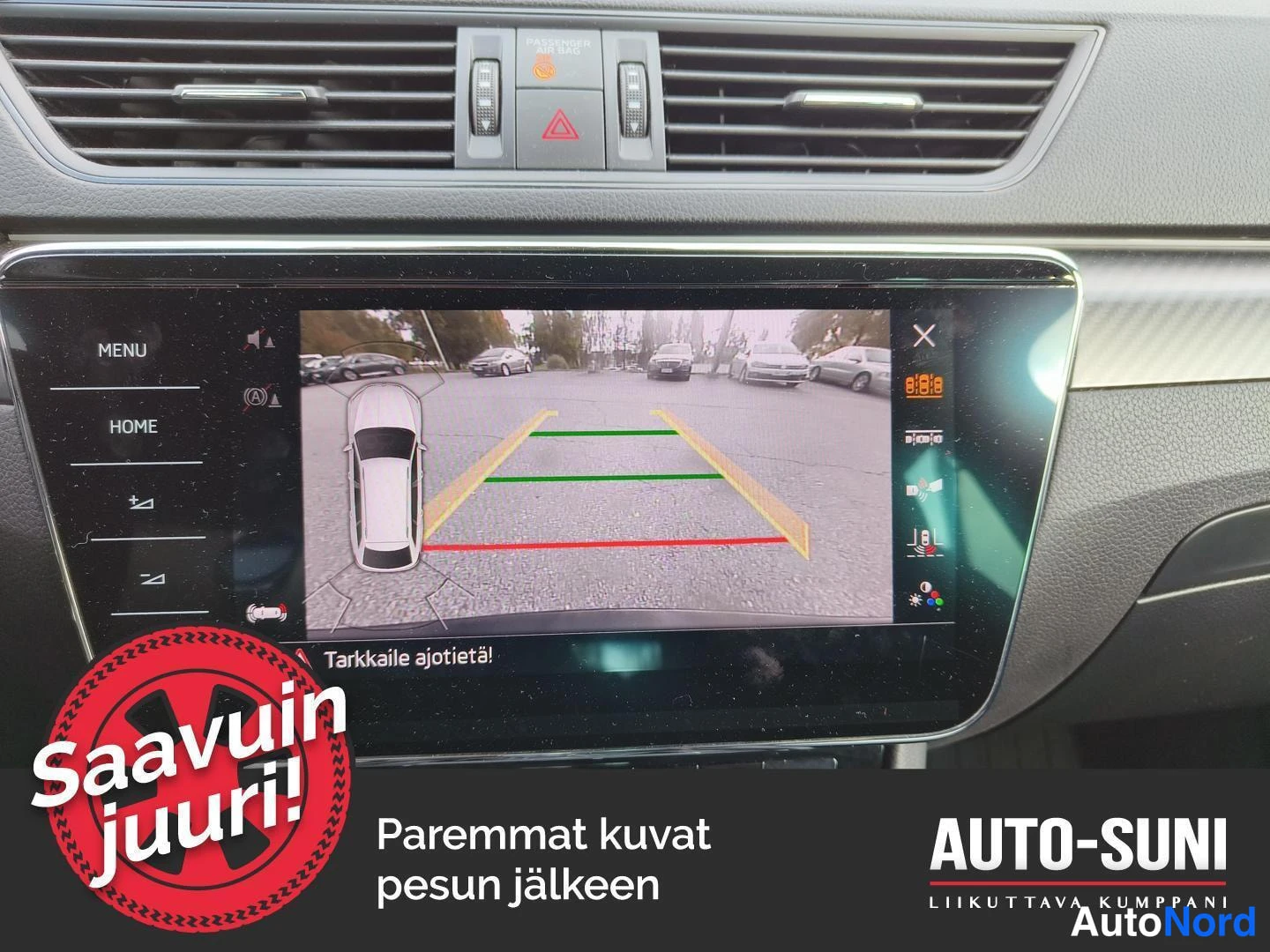 Muu: Kosketusnäytöllä näkyy peruutuskameran kuva parkkipaikasta ohjausviivoineen ja auton kuvitelineenä.