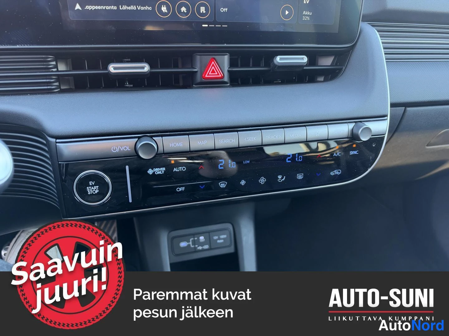 Muu: Keskikonsolin ilmastointipaneeli, jossa A/C- ja SYNC-merkinnot sekä lämpötila-asetukset 21.0.