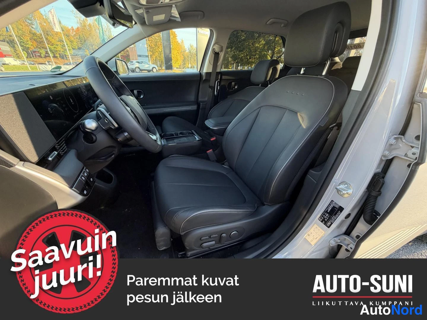 Muu: Auton etuistuin ja ohjaamo kuvattuna avatusta etiovesta; musta nahkainen kuljettajanistuin ja instrumenttinäyttö näkyvät.