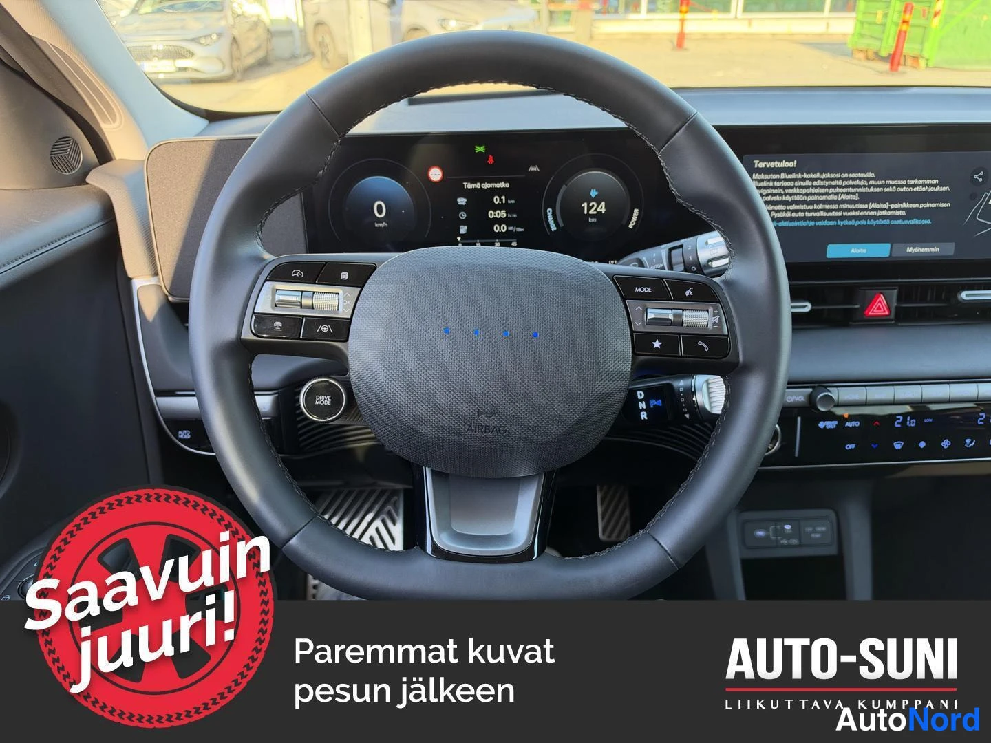 Muu: Lähikuva ohjauspyörästä ja mittaristosta; näytössä lukema 0 km/h sekä ilmastointi- ja ääniohjaimet.