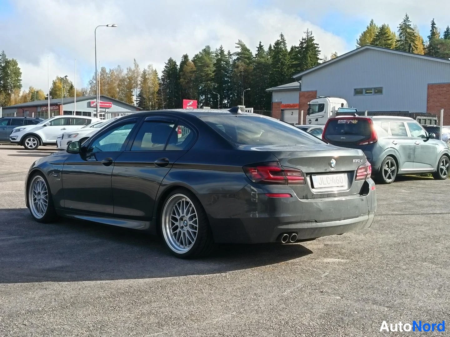 Takaviisto: Tummanharmaa BMW 530 d -sedaaninen henkilöauto kuvattu taka­viistöstä; näkyvät takavalot, -rekisterikilpi, '530 d' -merkintä ja kaksoisputkiston pakoputket, oik