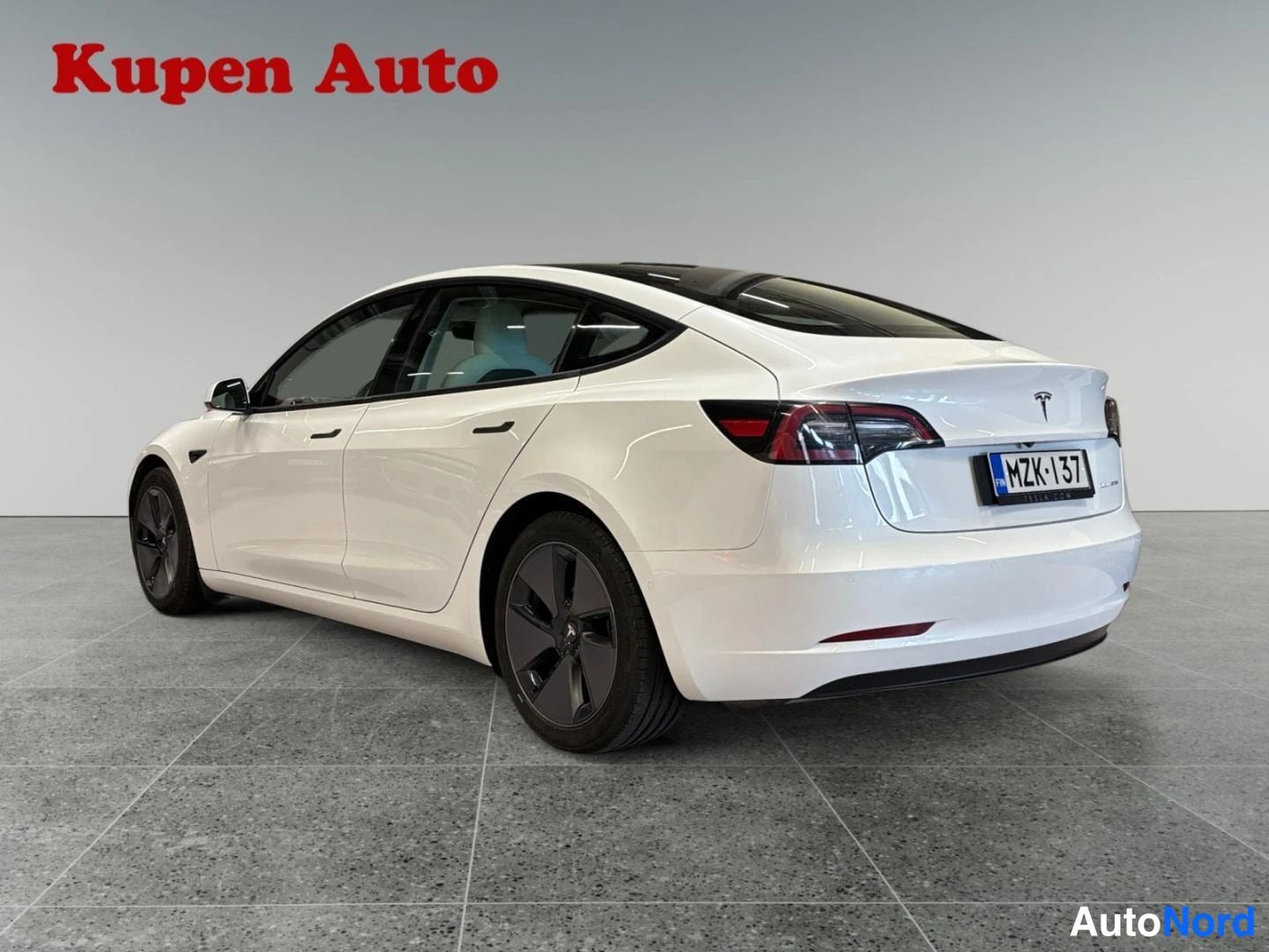 Takaviisto: Valkoisen Tesla Model 3 -sedanin takakulma, rekisterikilpi.