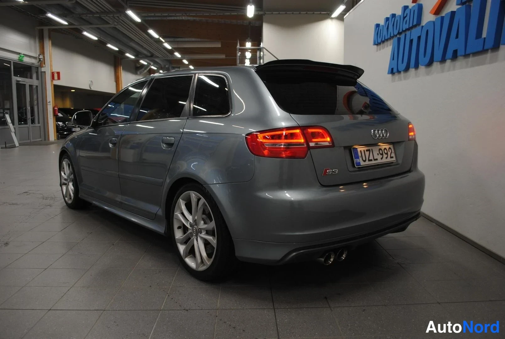 Takaviisto: Hopeanharmaa Audi S3 Sportback takaa oikealta katsottuna, kaksoispakoputki ja katonnen hatussa näkyvät.