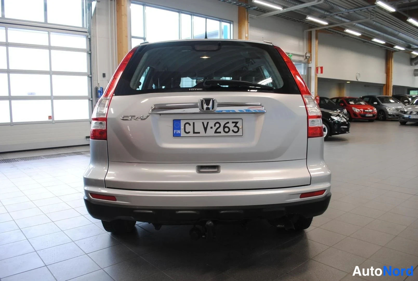 Takaa: Hopeanvärinen Honda CR-V suoraan takaa, Honda-merkintä, -rekisterikilpi ja vetokoulu näkyvissä.