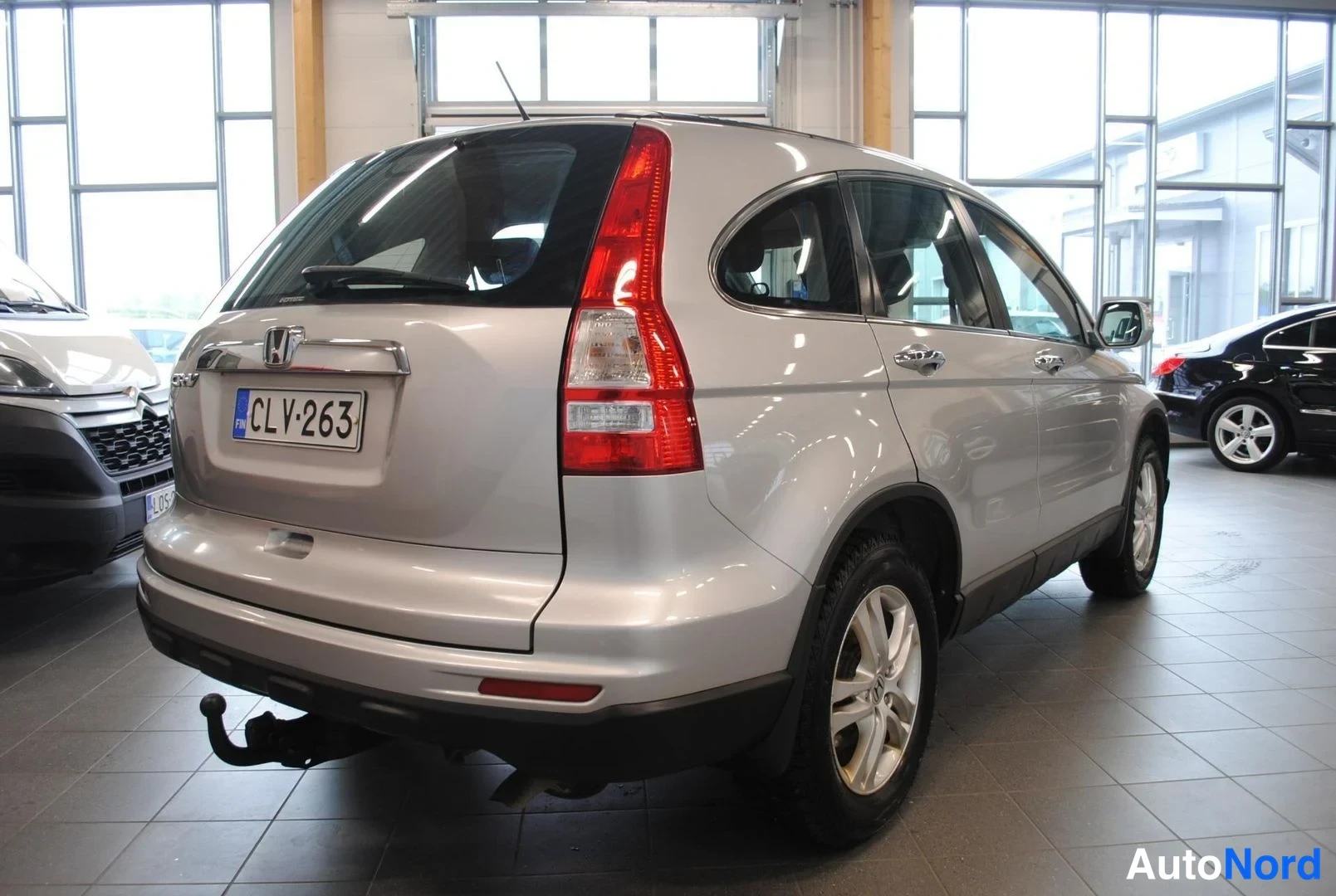 Takaviisto: Hopeanvärinen Honda CR-V -farmarikin takaa kulmasta kuvattuna sisätiloissa; rekisterikilpi ja takaosan hinauskoukku näkyvät.