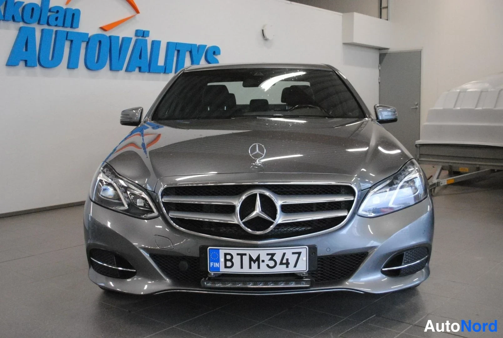 Edestä: Mercedes-Benz E-sarjan sedan edestäpäin, tummanharmaa kori ja rekisterikilpi