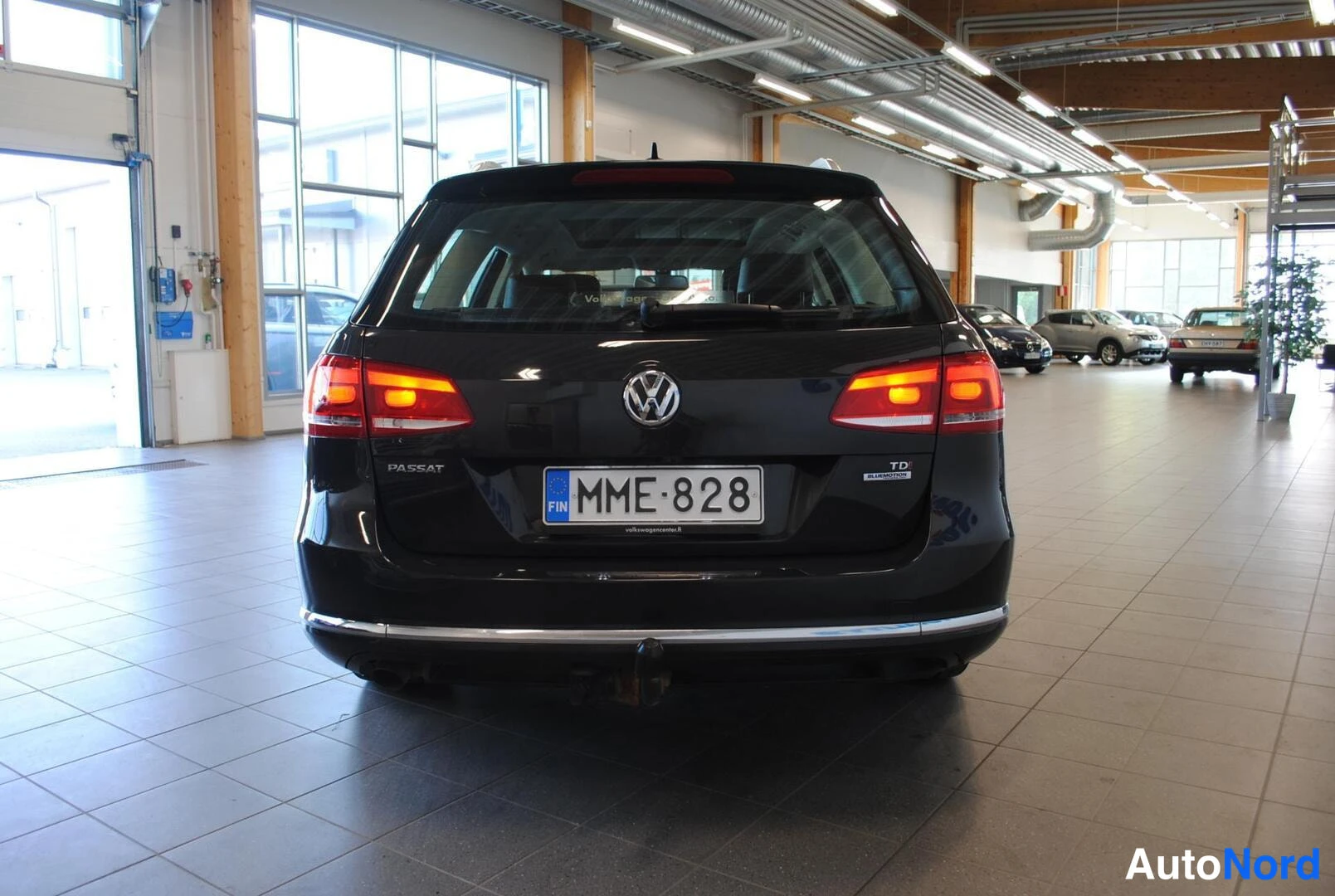 Takaa: Mustan farmariauton takaosa suoraan takaa, rekisteri, syttyneet takavalot, teksti PASSAT ja TDI BlueMotion.