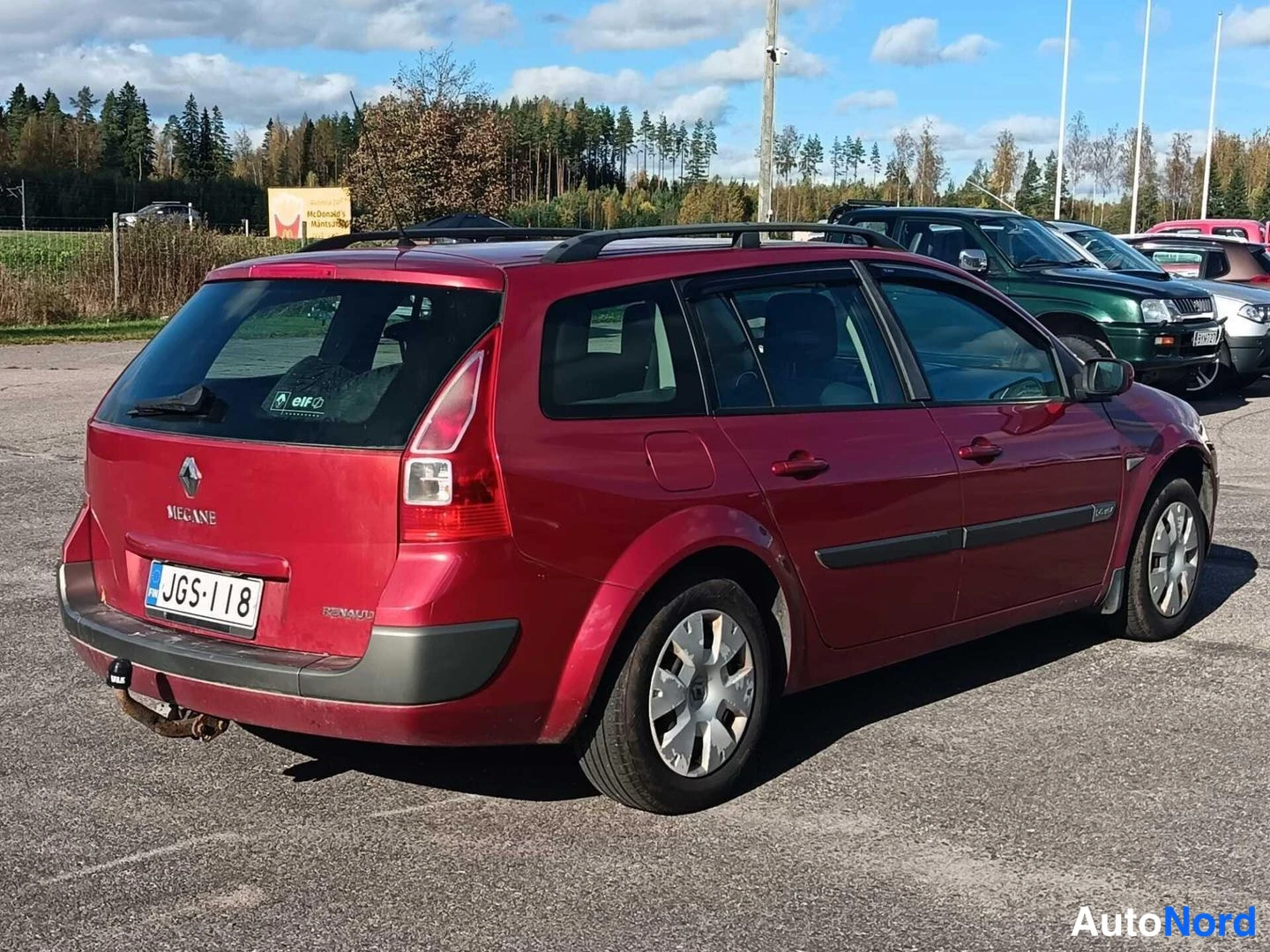 Takaviisto: Punainen Renault Megane Farmi takaa kolmannelta neljännekseltä; takaovessa MEGANE-teksti, takavilkun lähellä kattotankoreki ja rekisterikilpi.