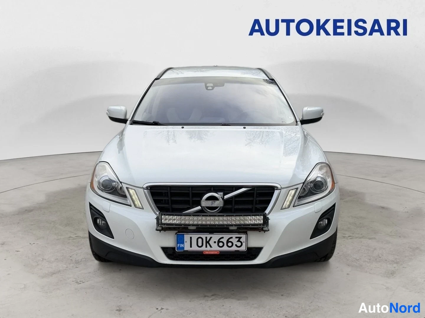 Edestä: Valkoinen auto suoraan edestä kuvattuna, etusäleikkö ja rekisterikilpi 1OK-663 näkyvissä.