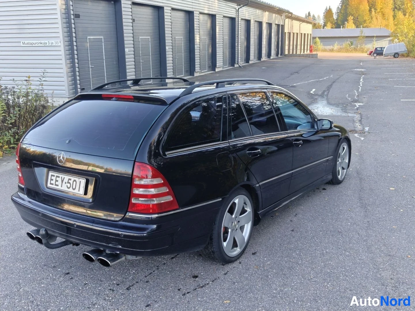 Takaviisto: Mustan Mercedes-Benz farmariauton takaosa vasemmalta; rekisterikilpi ja neljä pakoputkea näkyvät.