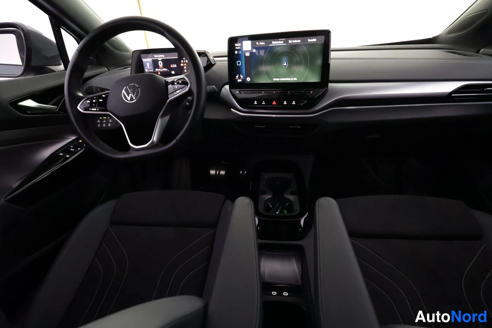 Muu: Ohjaamo näkyvissä: Volkswagen-ohjauspyörä, digitaalinen mittaristo ja keskikonsolin infotainment-näyttö, mustat istuimet.