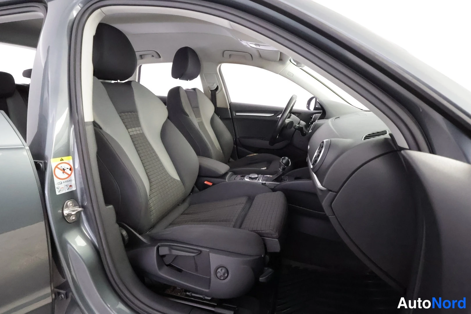 Edestä: Audi A3:n etusomat kankaasta, avoin etuovi ja osa kojelautaa ja vaihteenvalitsinta.