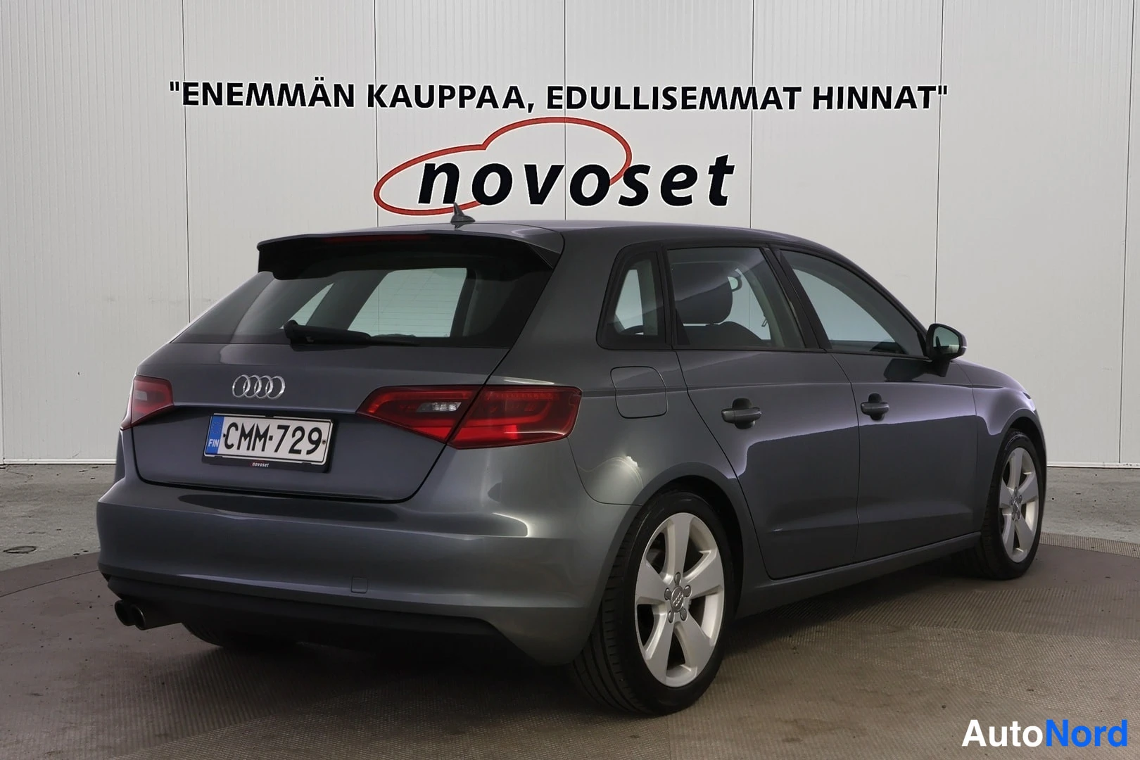 Takaviisto: Harmaa Audi A3 Sportback takaviistöstä oikealta kuvattuna autosalon seinustalla.