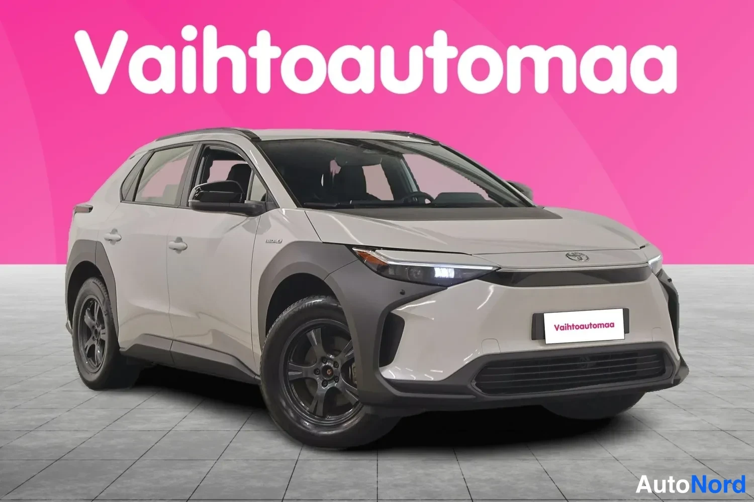 Etuviisto, nokka oikealle: Toyota bZ4X -sähköauto vaaleanbeige-yllä kuvattu kolmivartalo-otteesta keulasta oikealle, tummat pyöränkaaret ja tummat vanteet.