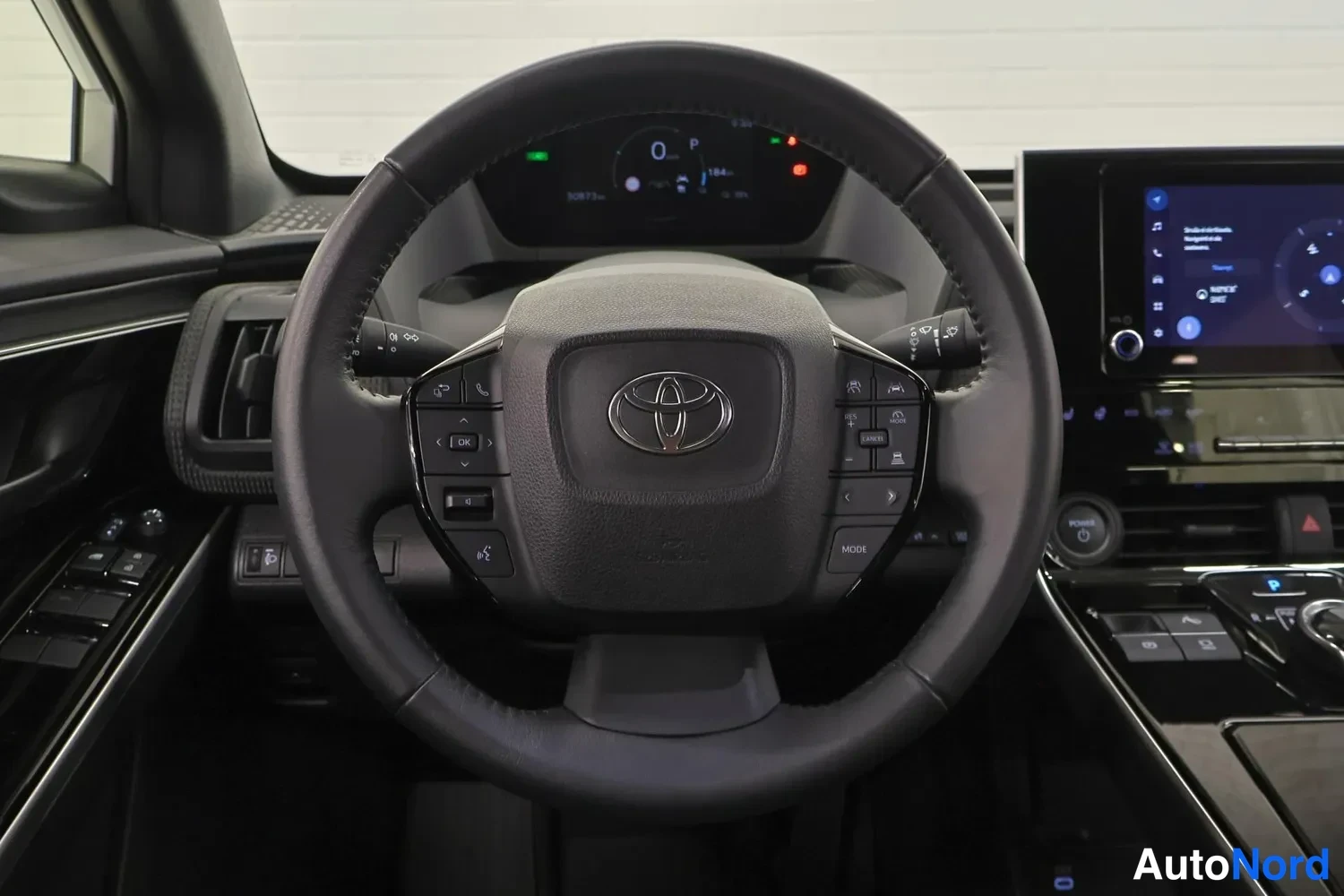 Muu: ohjauspyörän lähikuva Toyota-emblemillä, mittaritaulu näkyy taustalla