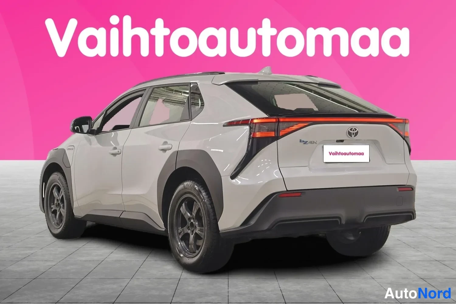 Takaviisto: Auton takanurkku: valkoharmaa Toyota bZ4X -maasturi, tunnustaukset ja perävilkut näkyvät.