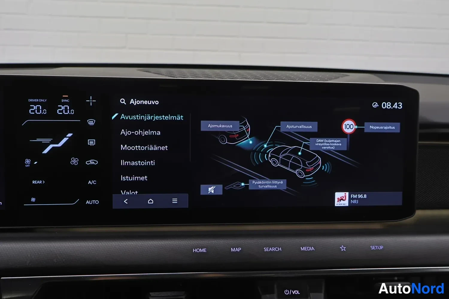 Yksityiskohta: Auton infotainment-näyttö, jolla näkyy Ajoneuvo-valikko ja avustinjärjestelmien asetukset suomeksi.