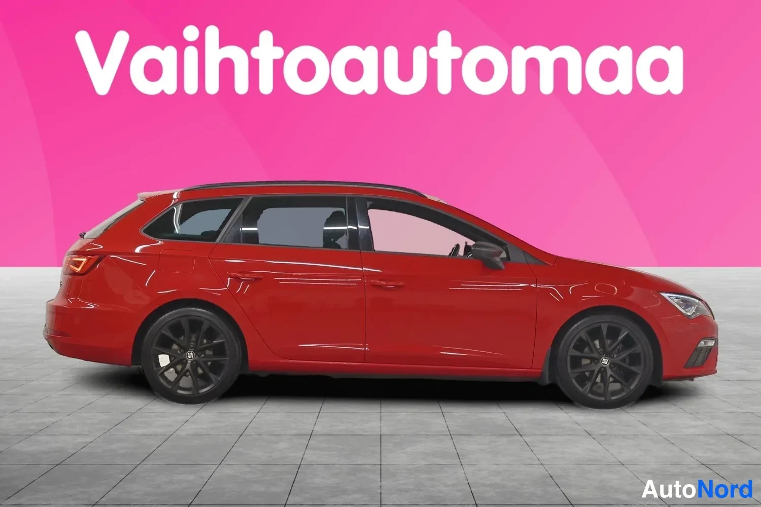Etuviisto, nokka oikealle: Punaisen Seat Leon ST -farmariauton sivuprofiili, mustat kevytmetallivanteet ja kattokaaret näkyvät.