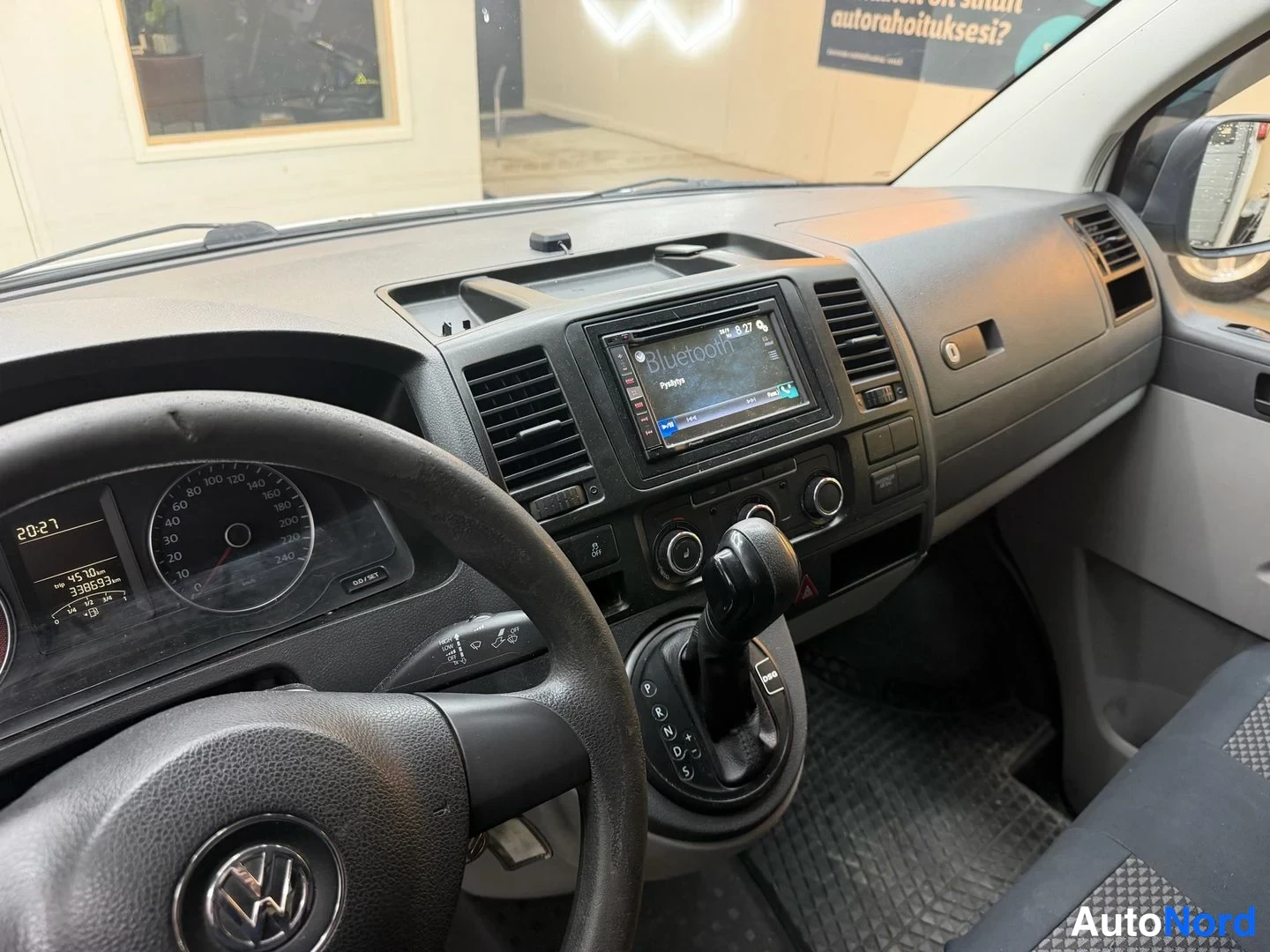 Muu: Ohjaamon kojelauta, Volkswagen-ohjauspyörä, automaattivaihteen valitsin ja Bluetooth-näyttävä autoradio.