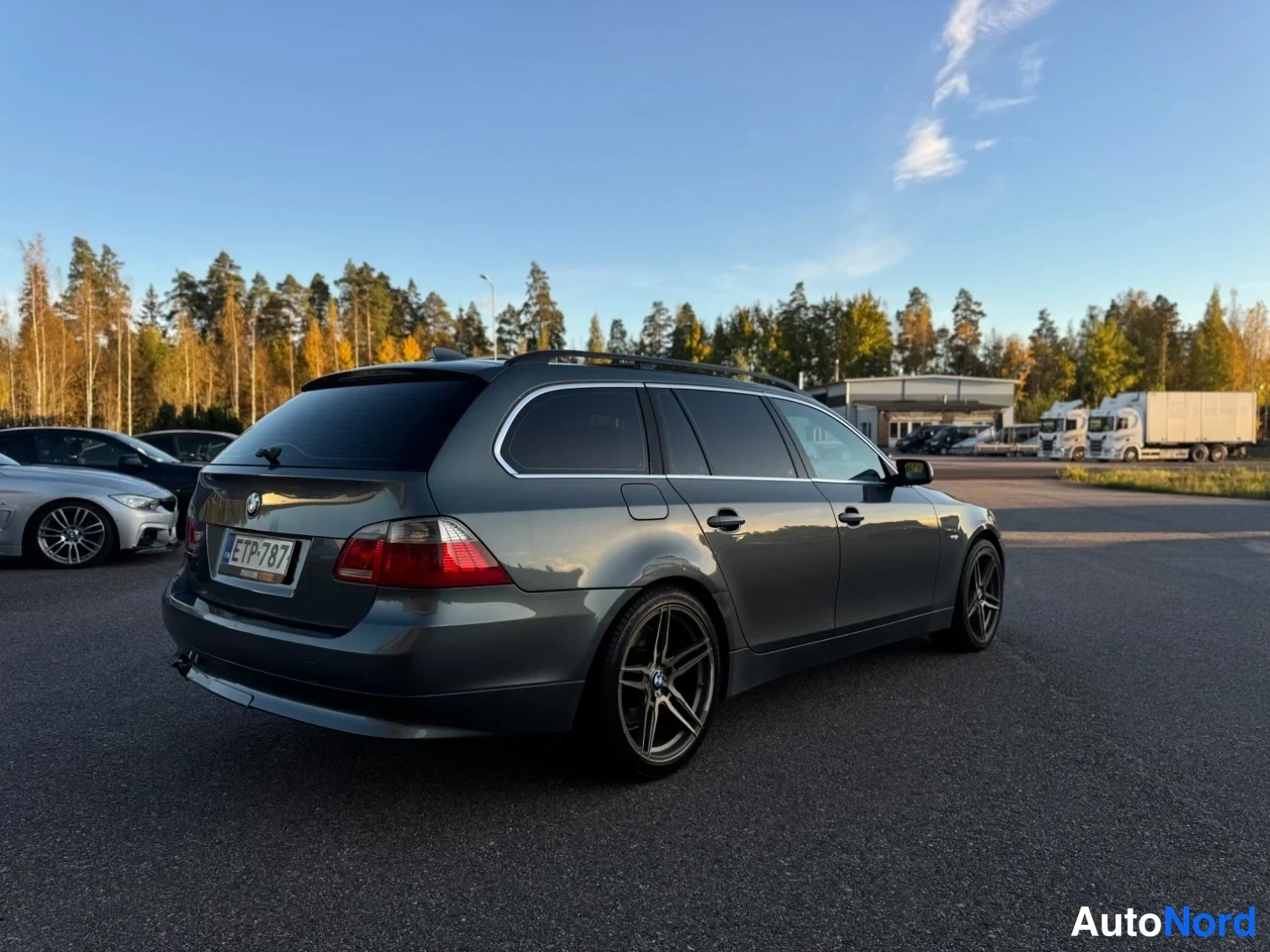 Takaviisto: BMW-farmari takaviistolta oikealta, rekisterikilpi, kattotelineet ja tummat vanteet.