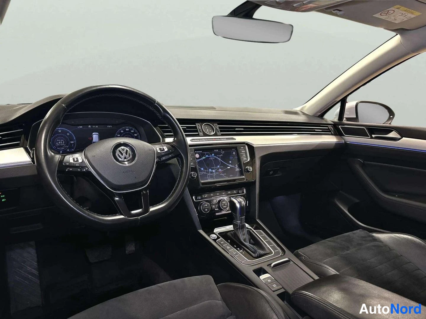 Muu: Auton sisätilat kuljettajan puolelta: Volkswagen-ohjauspyörä, digitaalinen mittaristo, kosketusnäytöllinen infotainment-järjestelmä navigointikartalla, automaat