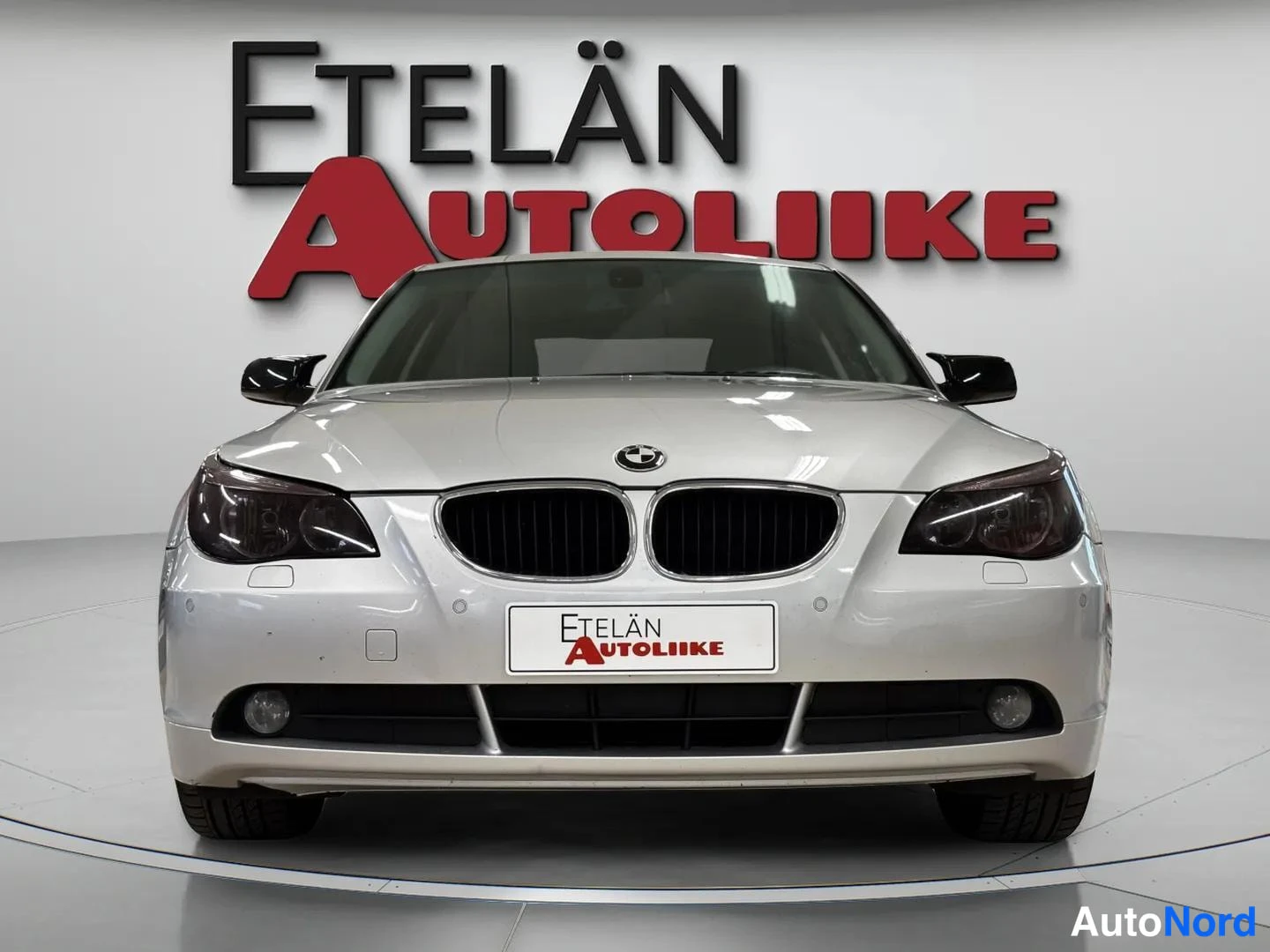 Edestä: BMW 520i -sedan suora etunäkymä, BMW-merkki ja etukiiltokytkin studiossa.