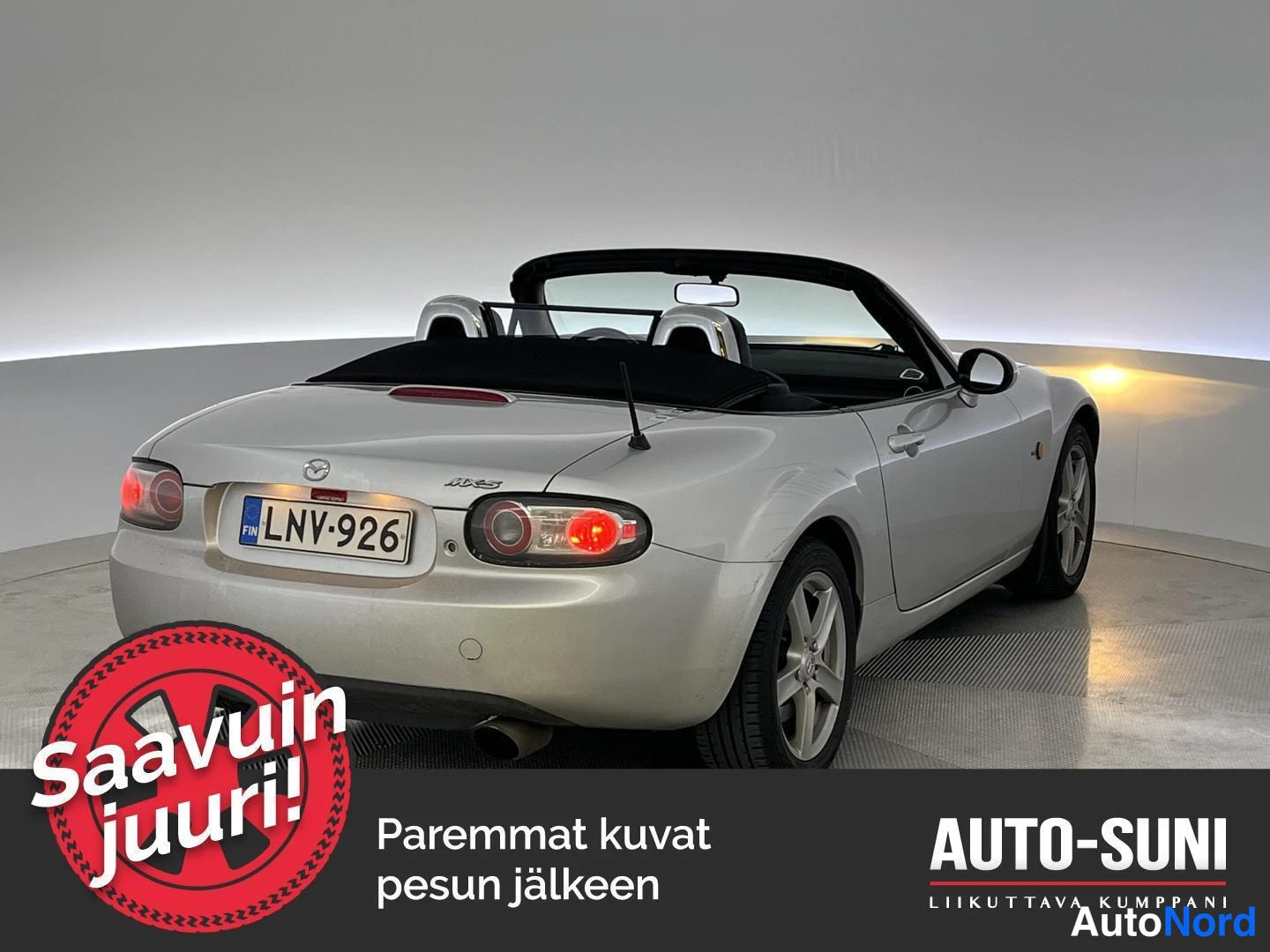 Takaa: Hopeanvärinen avo-Mazda MX-5 suoraan takaa, pehmeä katto laskettuna, rekisteritunnus.