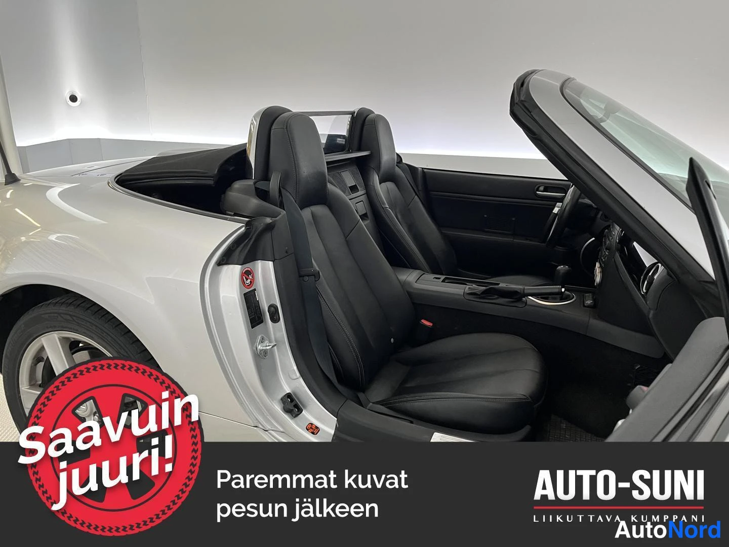 Etuviisto, nokka oikealle: Mazda MX-5:n sisusta avattuna: kaksi istuinta, musta sisusta ja takana kiinteät kaaret.