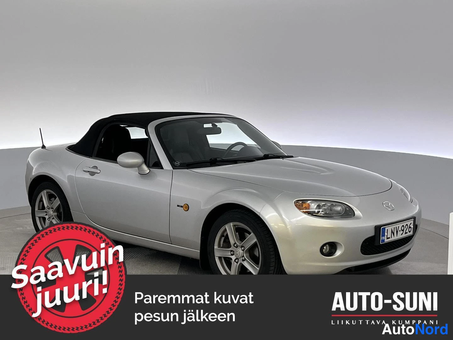 Etuviisto, nokka oikealle: Mazda MX-5 avoauto, hopea kori ja musta pehmeä katto,.