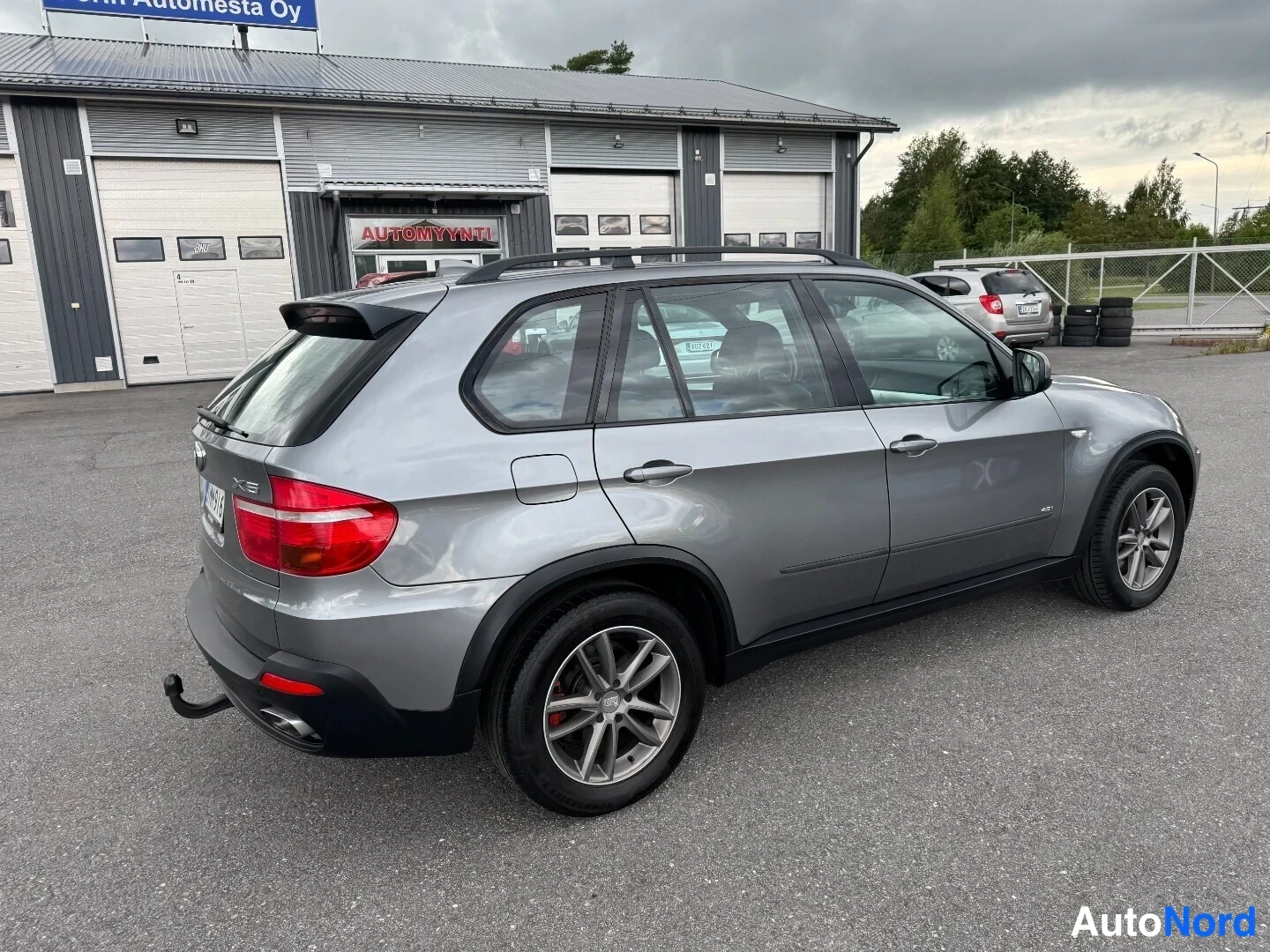 Takaviisto: BMW X5:n takaosa ja kylki harmaana, rekisterikilpi ja vetokoulu näkyvät.