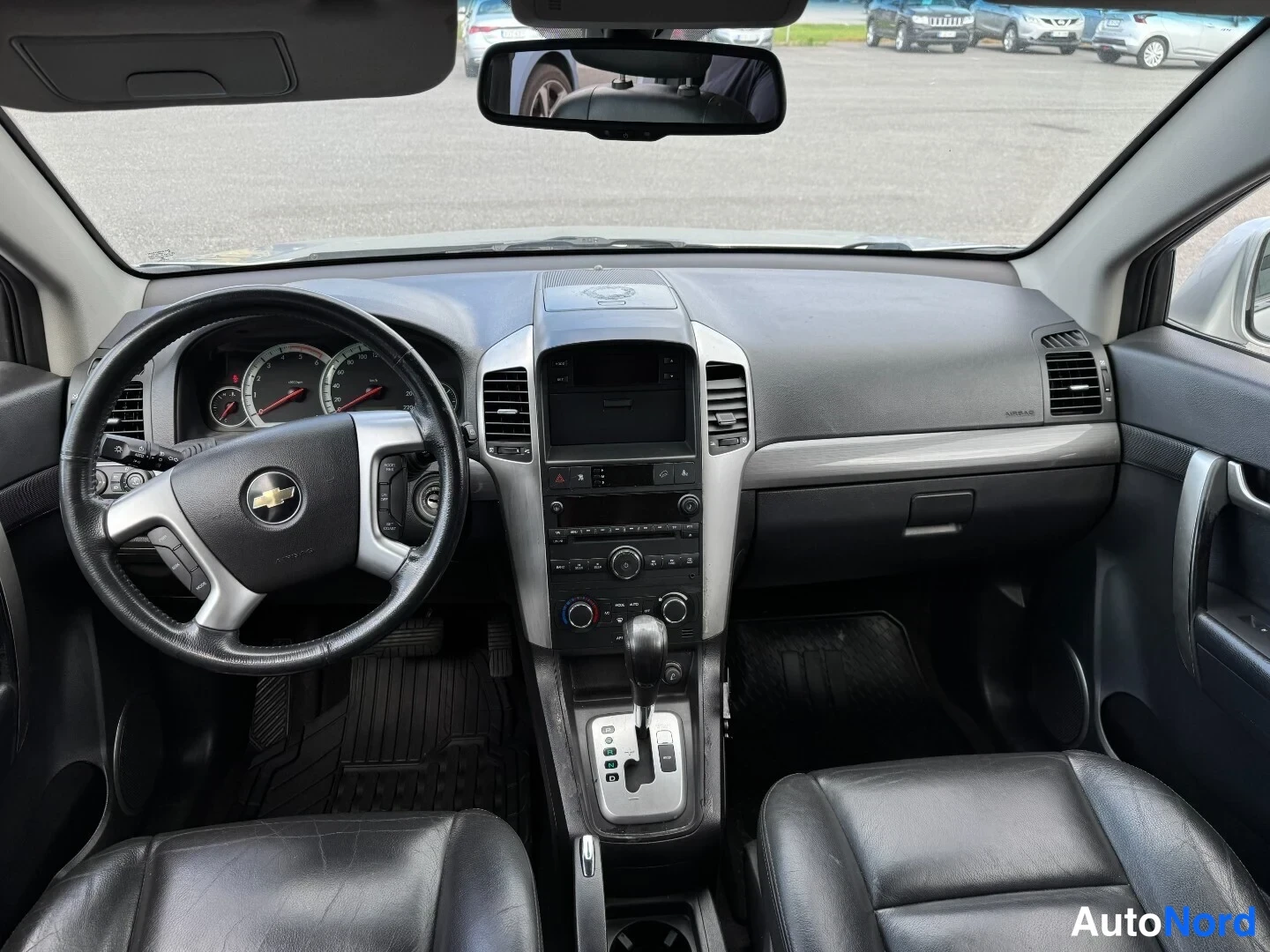 Edestä: Sisätilojen kuva Chevrolet Captivasta: ohjauspyörä, kojelauta ja tummat etuistuimet näkyvät yleiskuvana.