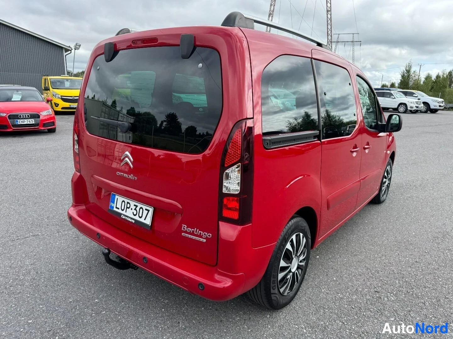 Takaviisto: Citroën Berlingo:n perä ja oikea kylki punaisena; rekisterikilpi, kattotankorakenne ja takavilkut näkyvät.