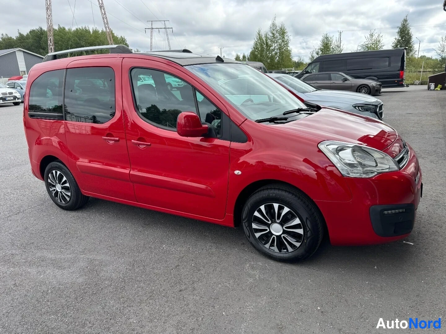 Etuviisto, nokka oikealle: Punainen Citroen Berlingo -pakettiauto kolmannelta kulmalta kuvattuna, keula oikealla.